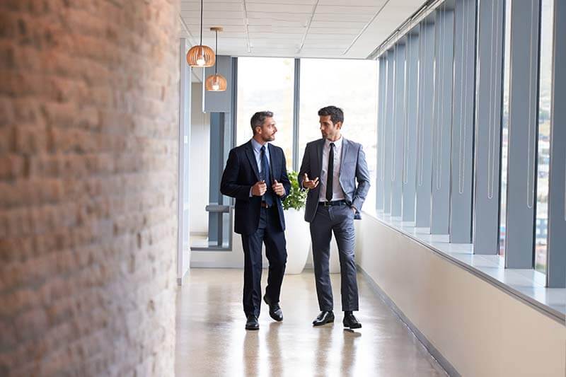 Two partners walking down a hallway having a conversation